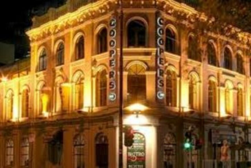 Heritage-listed Coopers Inn hotel, floodlit at night on a corner block.
