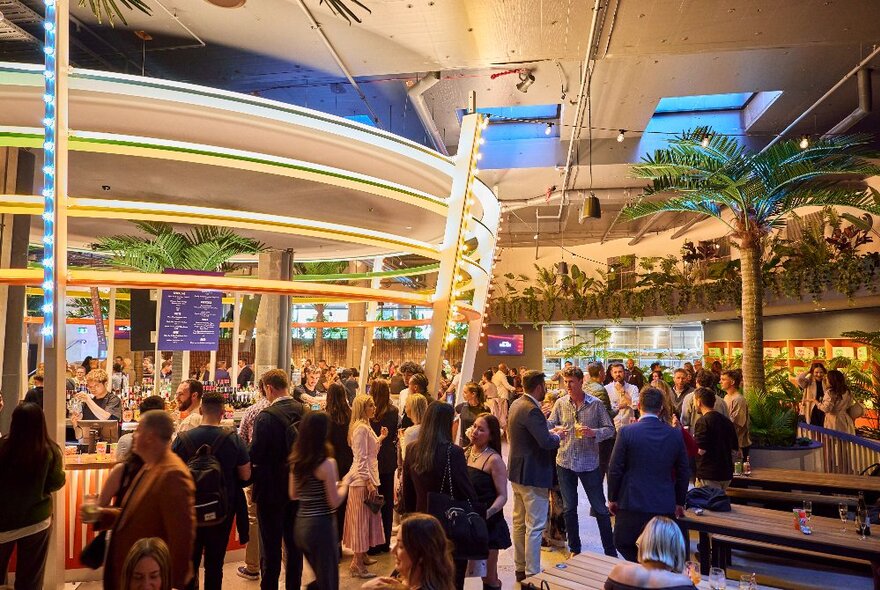 Interior of Doglands venue with a very large 360-degree illuminated bar, surrounded by people drinking and socialising.